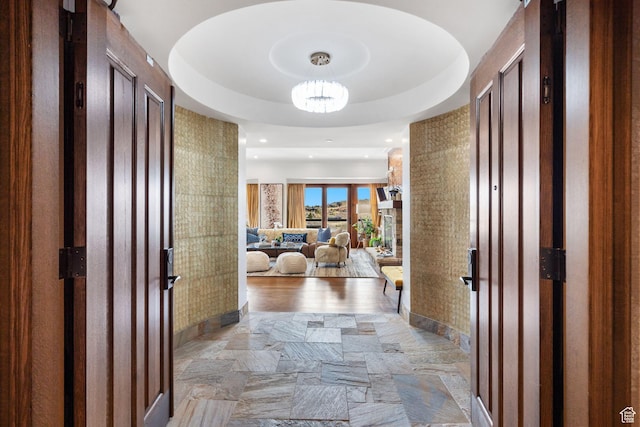 hallway featuring light stone finish floors, a chandelier, baseboards, and recessed lighting