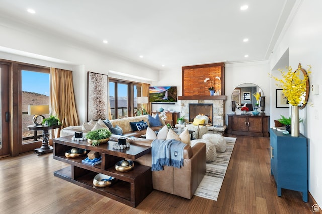 living room featuring healthy amount of natural light, arched walkways, ornamental molding, wood finished floors, and recessed lighting