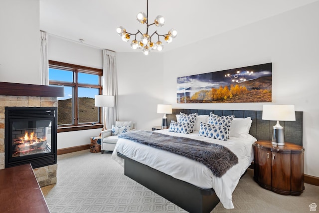 bedroom with baseboards, a stone fireplace, a chandelier, and carpet flooring