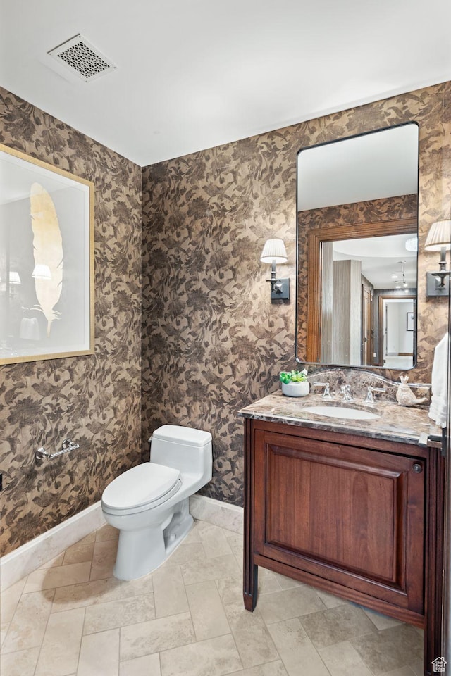 bathroom featuring baseboards, toilet, and vanity