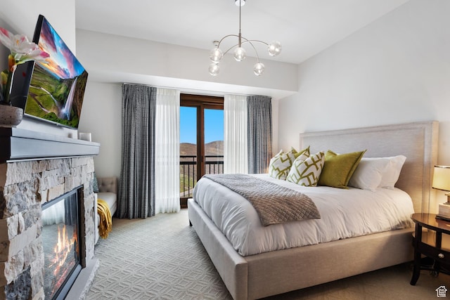 bedroom with access to outside, carpet, a stone fireplace, and a chandelier
