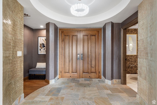 entryway with stone tile flooring, baseboards, and a chandelier