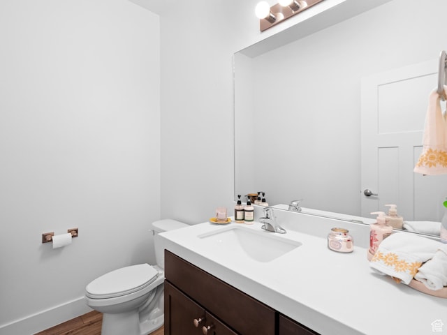 bathroom with wood finished floors, toilet, vanity, and baseboards