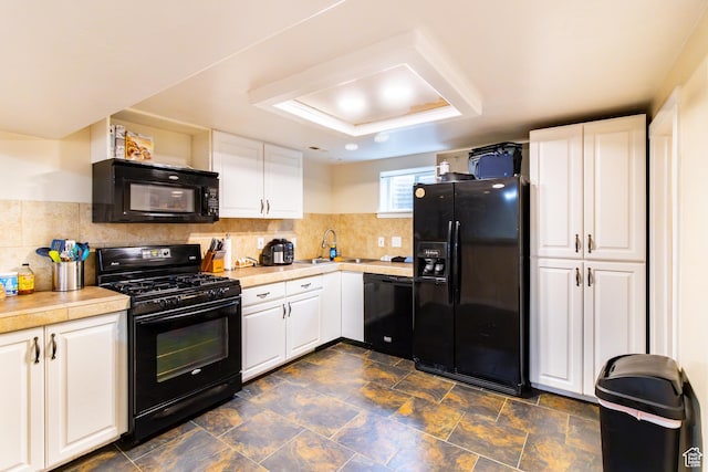 kitchen featuring black appliances, a tray ceiling, light countertops, and white cabinets