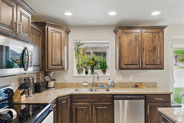 kitchen with stainless steel appliances, a sink, recessed lighting, dark brown cabinets, and light stone countertops