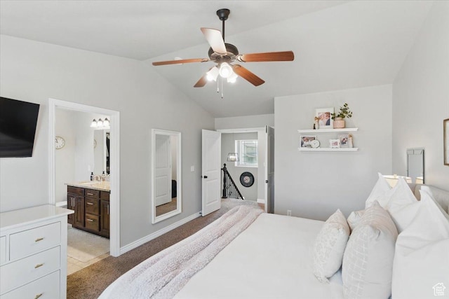 bedroom featuring vaulted ceiling, light carpet, a ceiling fan, baseboards, and ensuite bath