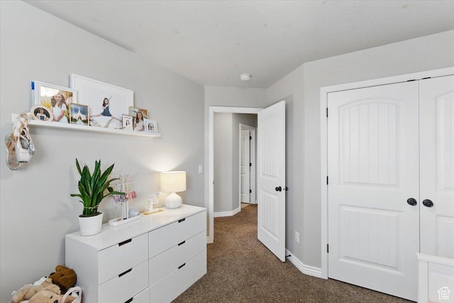 bedroom with dark carpet, baseboards, and a closet