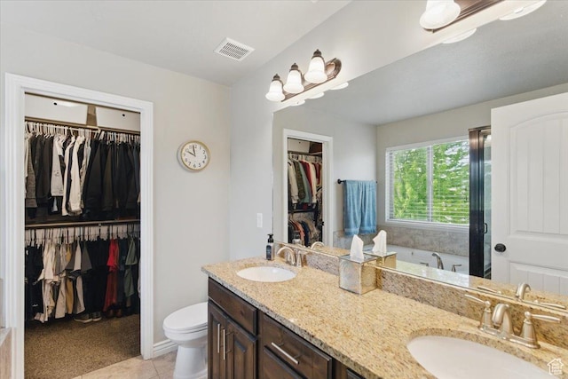 full bathroom featuring double vanity, toilet, a spacious closet, tile patterned floors, and a tub