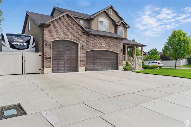view of front of house with brick siding, concrete driveway, a gate, stucco siding, and roof with shingles