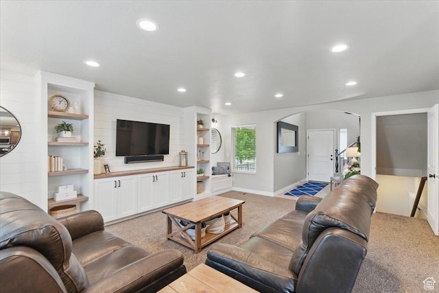 living area with light carpet, arched walkways, recessed lighting, and baseboards