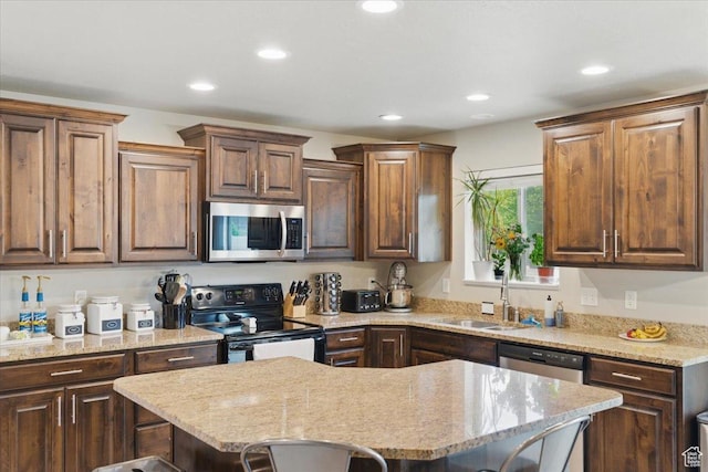 kitchen with stainless steel appliances, recessed lighting, a kitchen island, a breakfast bar, and a sink