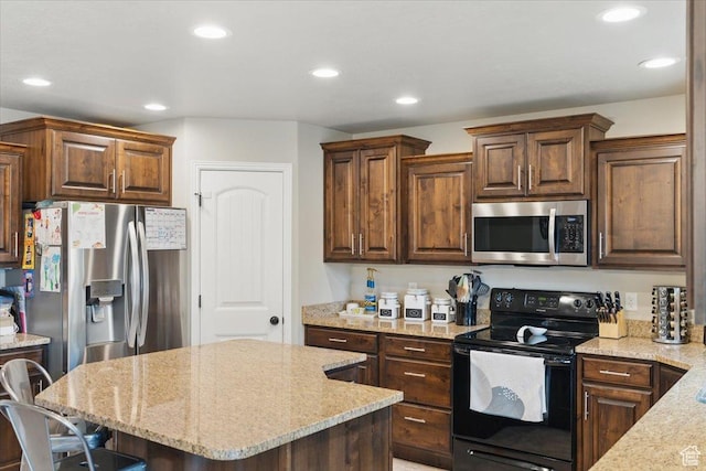 kitchen with appliances with stainless steel finishes, light stone counters, recessed lighting, a kitchen island, and a breakfast bar