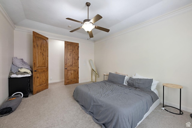 carpeted bedroom with baseboards, crown molding, ceiling fan, and a tray ceiling