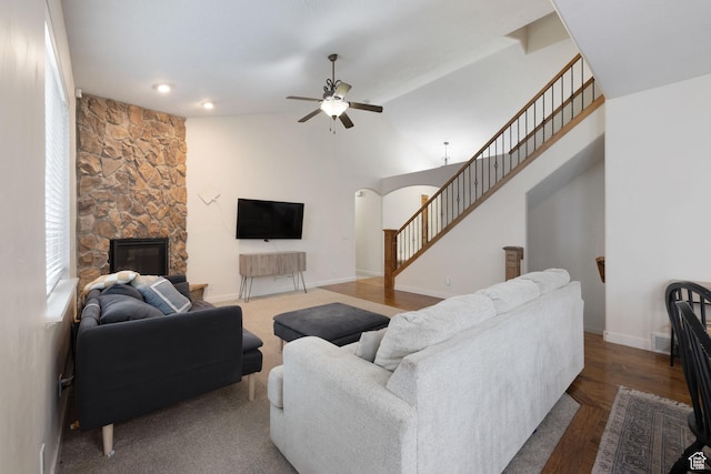 living area with stairway, a ceiling fan, a fireplace, arched walkways, and wood finished floors