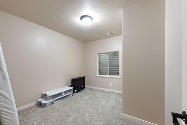 carpeted empty room featuring a textured ceiling and baseboards