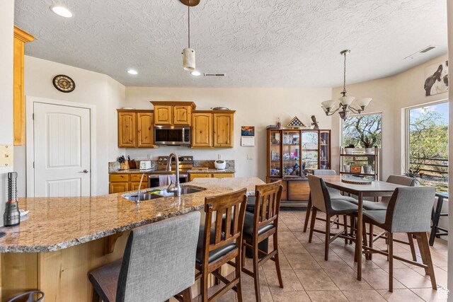 881 W Smithsonian Way, Apple Valley, UT 84737 - kitchen with appliances with stainless steel finishes, a chandelier, a kitchen breakfast bar, light tile patterned flooring, and a textured ceiling