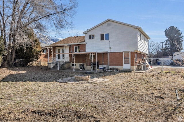 rear view of house featuring brick siding, fence, and a patio