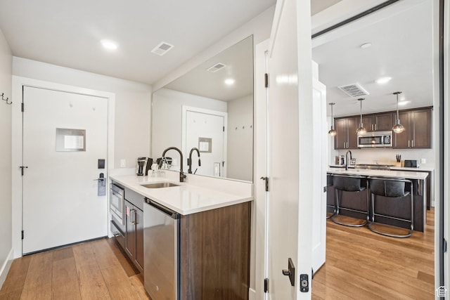 909 W Peace Tree Trl Unit 513, Kamas, UT 84036 - kitchen with stainless steel microwave, a sink, light wood-style floors, dark brown cabinets, and light countertops