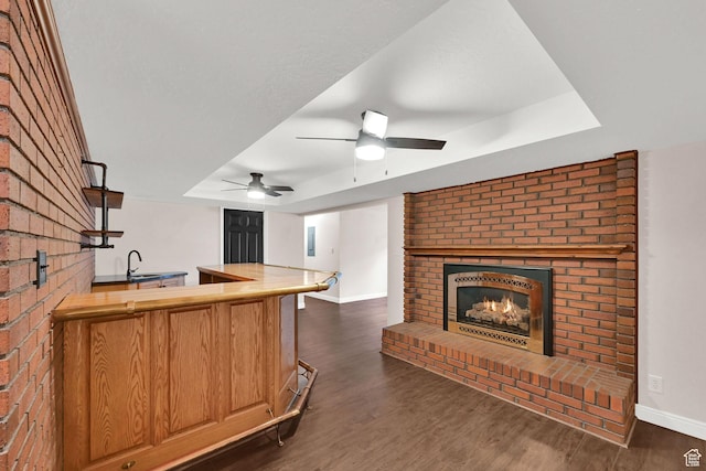3348 E Stonehill Ln, Cottonwood Heights, UT 84121 - kitchen featuring a raised ceiling, a sink, a brick fireplace, dark wood finished floors, and baseboards
