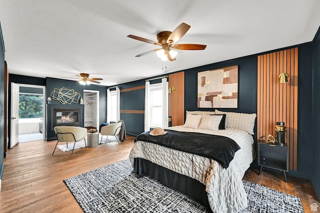3348 E Stonehill Ln, Cottonwood Heights, UT 84121 - bedroom with a glass covered fireplace, wood finished floors, and a ceiling fan