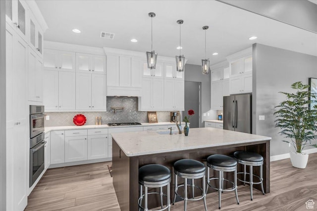 1865 N Park Grove Dr, Washington, UT 84780 - kitchen with appliances with stainless steel finishes, a sink, light wood-type flooring, a center island with sink, and tasteful backsplash