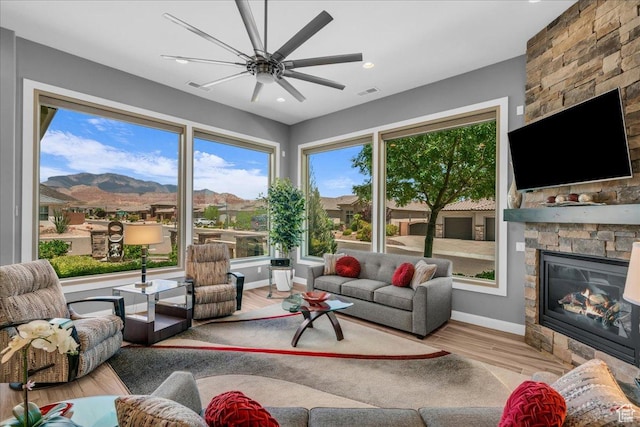 1865 N Park Grove Dr, Washington, UT 84780 - living room featuring a stone fireplace, wood finished floors, baseboards, a ceiling fan, and a mountain view