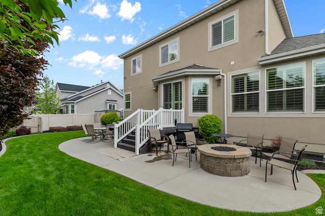 rear view of house with stucco siding, a patio, and a fire pit