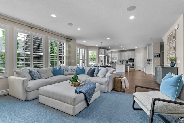 living area featuring recessed lighting, dark wood-type flooring, and a textured ceiling