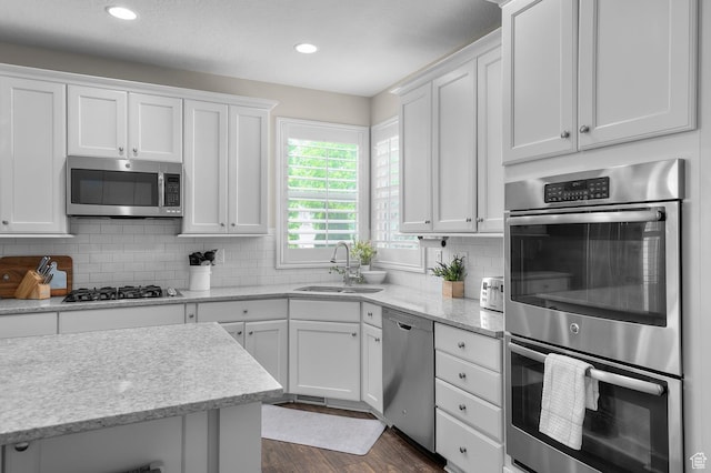 kitchen with appliances with stainless steel finishes, a sink, white cabinetry, and recessed lighting