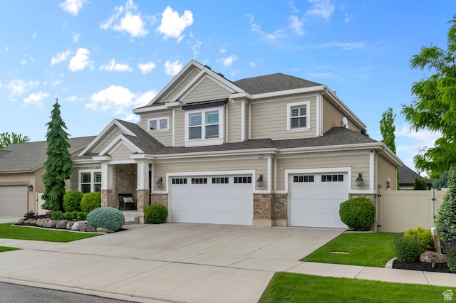 view of front facade with a garage, fence, driveway, and stone siding