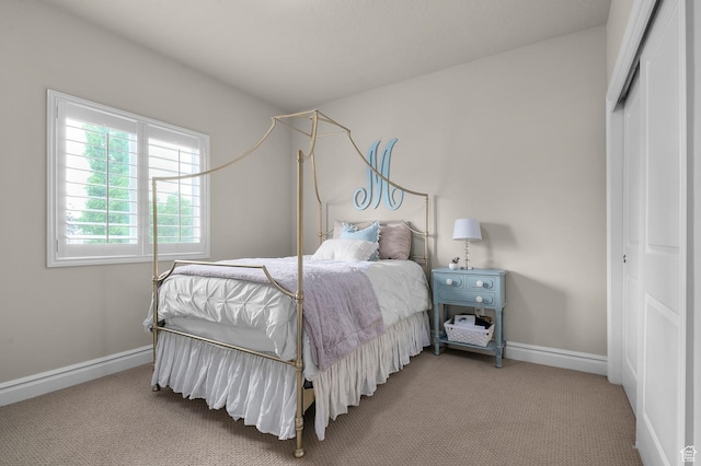 carpeted bedroom with a closet and baseboards