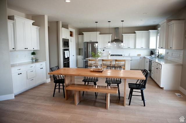 224 S Dry Creek Ln W, Vineyard, UT 84058 - kitchen with wall chimney exhaust hood, a sink, appliances with stainless steel finishes, backsplash, and light wood-style floors
