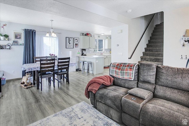 178 W Heidelberg Pl N, Stansbury Park, UT 84074 - living room featuring light wood-style floors, stairway, a chandelier, and baseboards