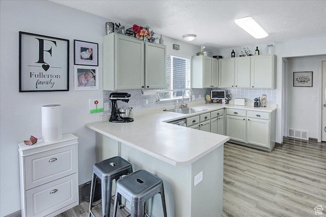 178 W Heidelberg Pl N, Stansbury Park, UT 84074 - kitchen featuring a sink, a kitchen bar, light countertops, light wood finished floors, and backsplash