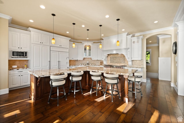 1515 E Maple St, Mapleton, UT 84664 - kitchen featuring stainless steel microwave, arched walkways, ornamental molding, a large island, and white cabinetry