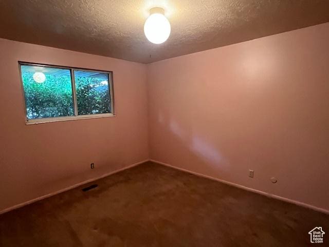carpeted empty room with a textured ceiling and baseboards
