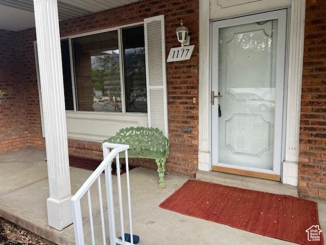 property entrance with brick siding and covered porch