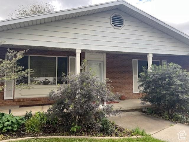 view of front facade featuring brick siding and a porch