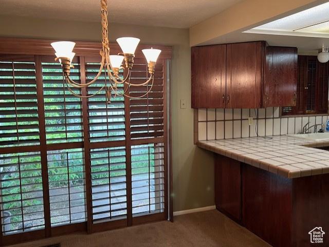 unfurnished dining area with carpet, a chandelier, plenty of natural light, and baseboards