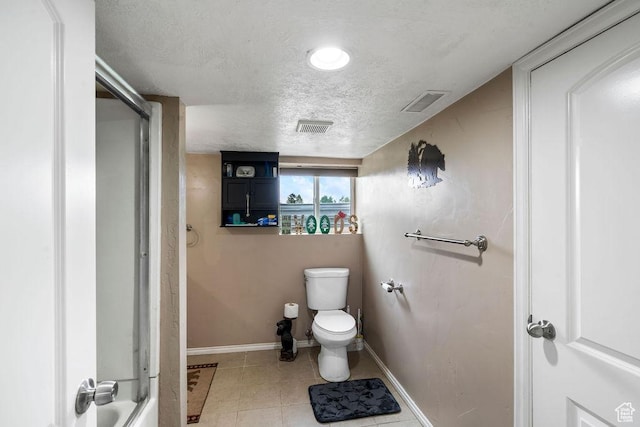 bathroom with baseboards, a shower, toilet, a textured ceiling, and tile patterned flooring