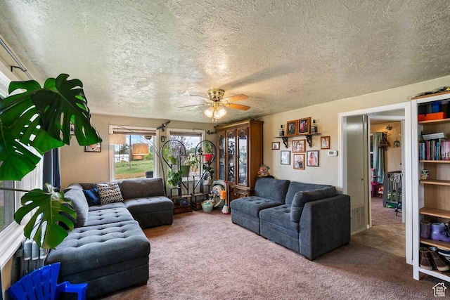 living area with ceiling fan, carpet, and a textured ceiling
