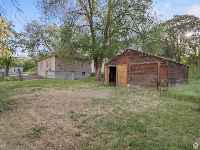 551 E 27th St, Ogden, UT 84403 - rear view of property featuring a detached garage, an outbuilding, and a yard