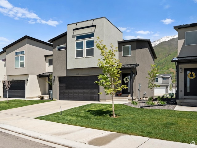 3957 S White Ash Dr, Mapleton, UT 84664 - modern home with an attached garage, stucco siding, concrete driveway, a front lawn, and a mountain view