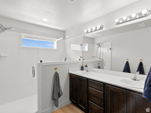 3957 S White Ash Dr, Mapleton, UT 84664 - bathroom featuring a stall shower, a textured ceiling, double vanity, and wood finished floors
