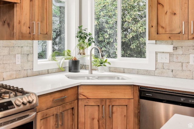kitchen featuring appliances with stainless steel finishes, a sink, brown cabinets, and light countertops