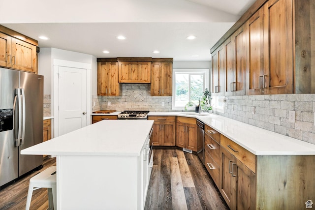 kitchen with appliances with stainless steel finishes, a sink, dark wood-style flooring, tasteful backsplash, and recessed lighting
