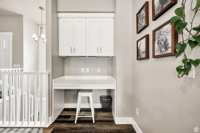 unfurnished office with dark wood-type flooring, baseboards, and a chandelier