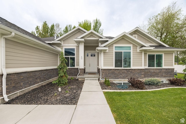 craftsman-style home featuring board and batten siding, stone siding, and a front yard