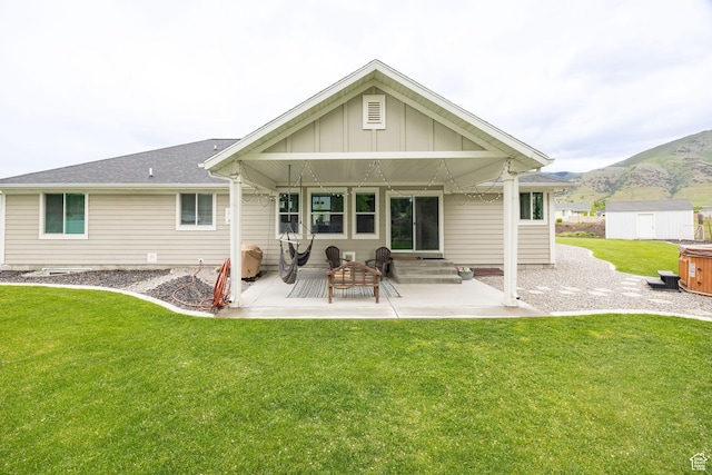 rear view of house featuring a patio area, a storage shed, a lawn, and board and batten siding
