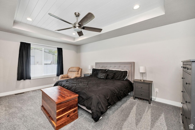 carpeted bedroom with a raised ceiling, baseboards, recessed lighting, and ceiling fan